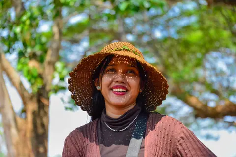 Smiling woman in a sun hat enjoying a sunny outdoor scene in Cambodia.