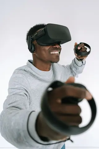Adult man wearing VR headset, smiling while interacting with virtual reality controls in a white room.