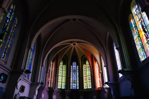 Stunning gothic cathedral interior featuring ornate stained glass windows and arched ceilings.