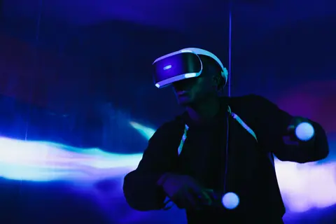 A person engaged in a virtual reality game using a VR headset and motion controllers.