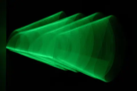 Dynamic abstract green light pattern captured in motion against a black backdrop, creating a modern artistic effect.