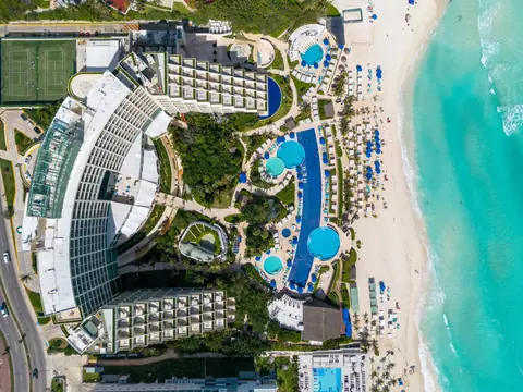Stunning aerial view of luxurious beachfront resort with pools in Cancun, Mexico.