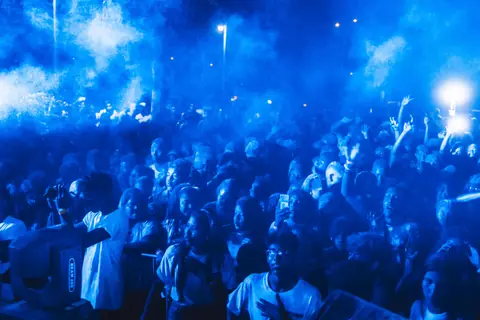 Lively concert scene with enthusiastic crowd bathed in blue light, capturing the essence of nightlife entertainment.
