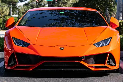 Vibrant orange luxury sports car captured outdoors on a sunny day in Miami.