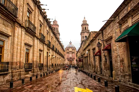 Historic cobblestone street leading to Morelia Cathedral, rich in architecture and culture.
