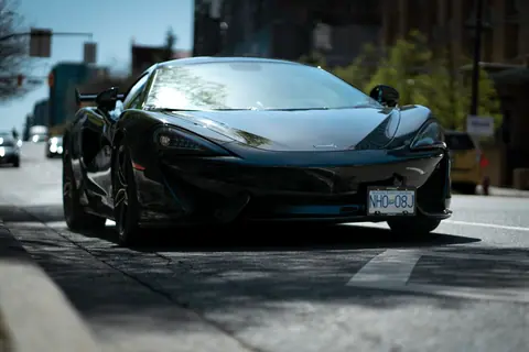 Sleek black sports car positioned prominently on a city street, exuding elegance and power.
