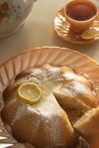 Delicious lemon bundt cake with sugar icing, served with a cup of tea.