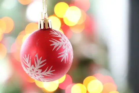 Close-up of a red Christmas bauble with decorative bokeh lights, perfect for festive themes.