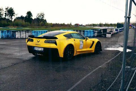 A vibrant yellow sports car on a wet race track in Ukraine, showcasing speed and style.