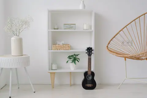 A modern minimalist living room setup featuring a ukelele, shelves, and stylish decor.