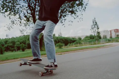 Young person mastering skateboarding moves in a park setting.