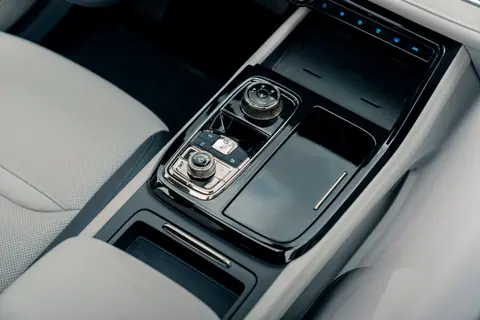 Close-up of a sleek and modern car center console with controls and storage areas.