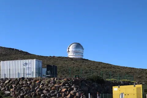 A large observatory dome sits on a hill beneath a clear blue sky, ideal for astronomy enthusiasts.