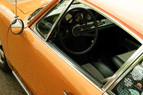 Close-up of a vintage orange coupe showcasing its classic interior and steering wheel.