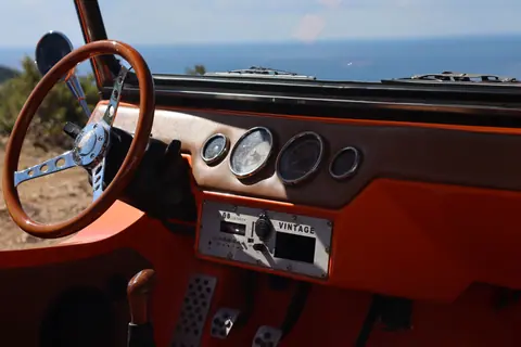 Explore the retro charm of a vintage car dashboard with a serene ocean view in the background.