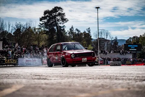 A thrilling drift car event featuring a red Volkswagen Golf II on an urban track.