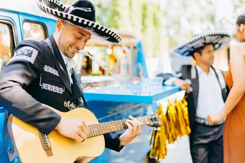 A joyful mariachi guitarist in traditional attire performing outdoors, embodying Mexican culture.
