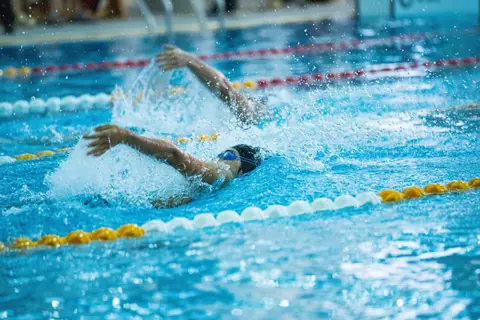 Dynamic shot of swimmers racing in a competitive swimming pool, emphasizing speed and skill.