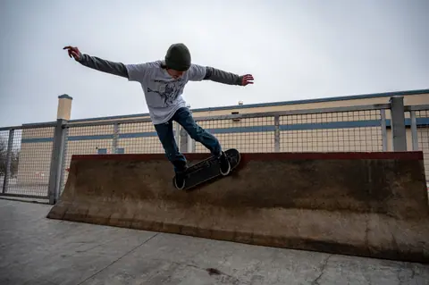 Skateboarder executing a trick on a ramp at an outdoor skatepark, showcasing balance and motion.