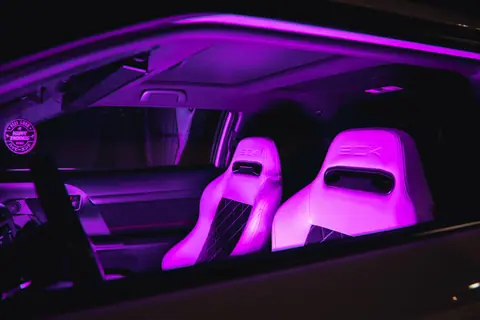 Luxury car interior with neon purple illuminated leather seats, creating a modern and vibrant ambiance.