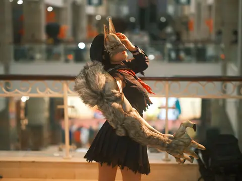A person in detailed cosplay costume featuring a wolf arm in an indoor environment.