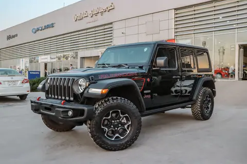 Black Jeep Wrangler Rubicon parked at a dealership showcasing its rugged design and glossy finish.