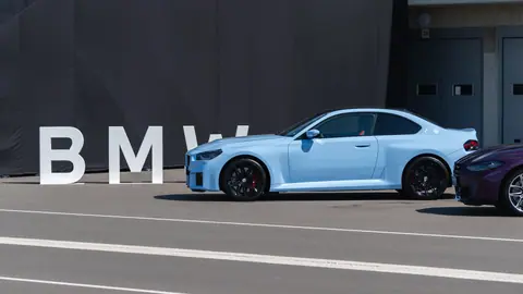 A modern, baby blue BMW parked in an outdoor location with a black backdrop.