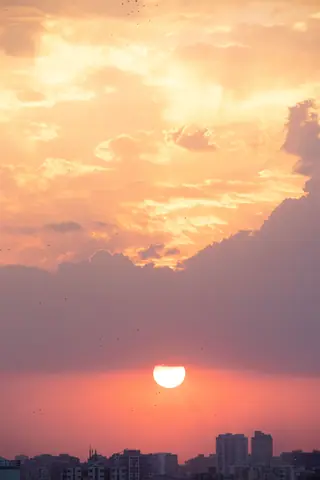 A breathtaking sunset over a city skyline in Gujarat, India, with vibrant colors and dramatic clouds.