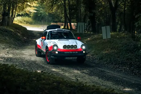 Vintage rally car driving through a scenic forest path in Southampton, UK.