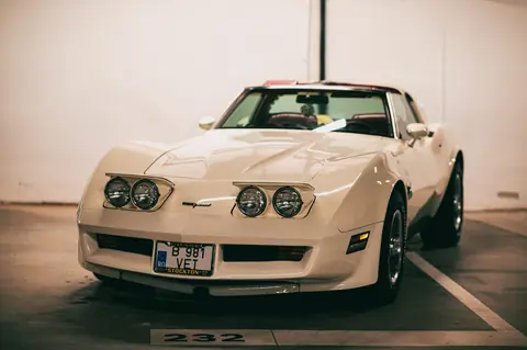 Close-up of a vintage white sports car parked in an indoor garage setting.