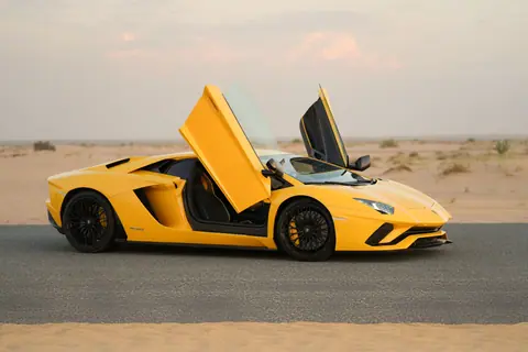 Striking yellow Lamborghini Aventador parked on a desert road with open doors, showcasing luxury in Dubai.