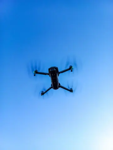 Aerial shot of a drone flying against a clear blue sky, showcasing modern technology.
