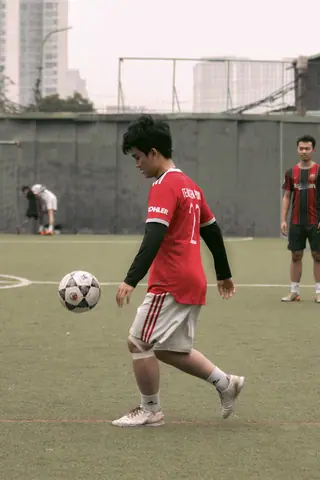 Teenagers in sports uniforms playing soccer on an outdoor field, showcasing action and teamwork.