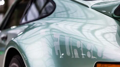 Close-up of a mint green classic car with detailed reflections, showcasing its vintage allure and elegant design.