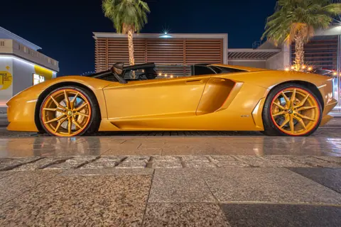 A sleek yellow sports car parked in Dubai's cityscape at night, showcasing elegance and luxury.