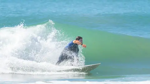 Surfer skillfully rides a wave, showcasing agility and balance in perfect summer conditions.