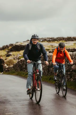 Two cyclists ride along a picturesque road in Inishmore, Ireland.