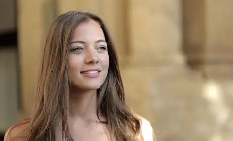 A beautiful portrait of a smiling young woman with long hair in a natural outdoor setting.