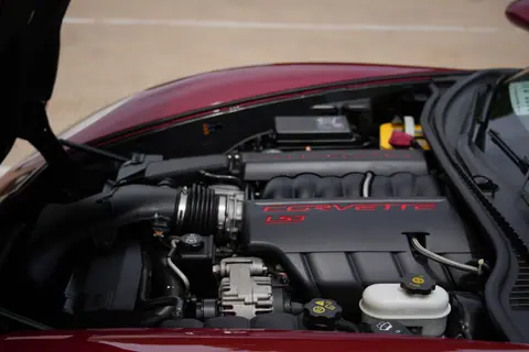 Detailed view of a Chevrolet Corvette LS3 engine under the hood of a red sports car in Wichita Falls, Texas.