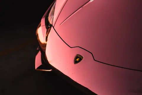 Artistic close-up of a luxury sports car hood with a black background.