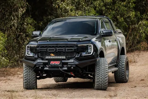 A rugged, black off-road truck poised on a dirt path amidst lush greenery, showcasing strength and adventure.