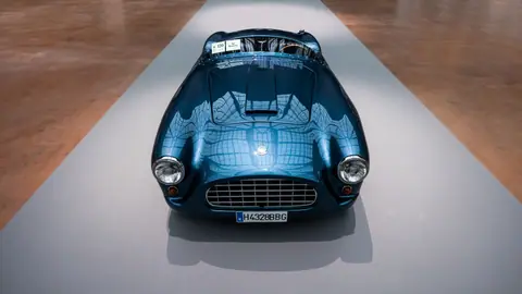 Front view of a polished blue vintage car on display indoors, showcasing classic design.