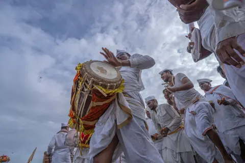Men in traditional attire playing drums during a festival in Pandharpur, India.