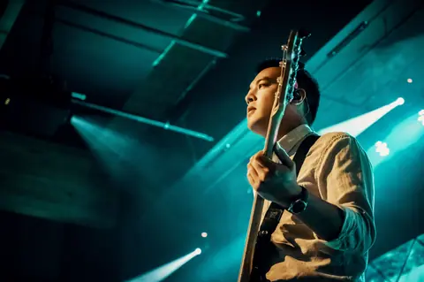 Guitarist performing live on stage under dramatic lighting, capturing a musical moment.