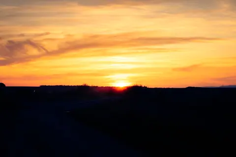 Captivating sunset with orange and yellow hues against a silhouetted horizon.