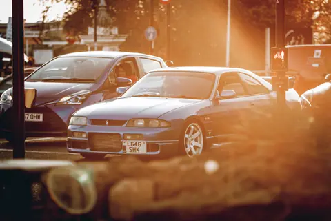 Capture of urban cars at sunset, showcasing a Nissan Skyline in a city setting.