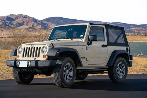 A Jeep Wrangler parked outdoors with Colorado mountains in the background.
