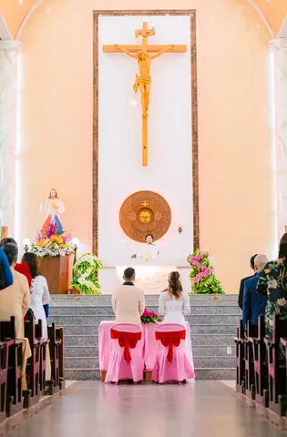 Bride and groom at the altar during a church wedding ceremony with floral decorations.