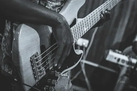 A black and white shot of a musician playing an electric guitar, focusing on hand and strings.