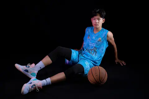 Young basketball player in blue sports uniform posing confidently in a studio setting.